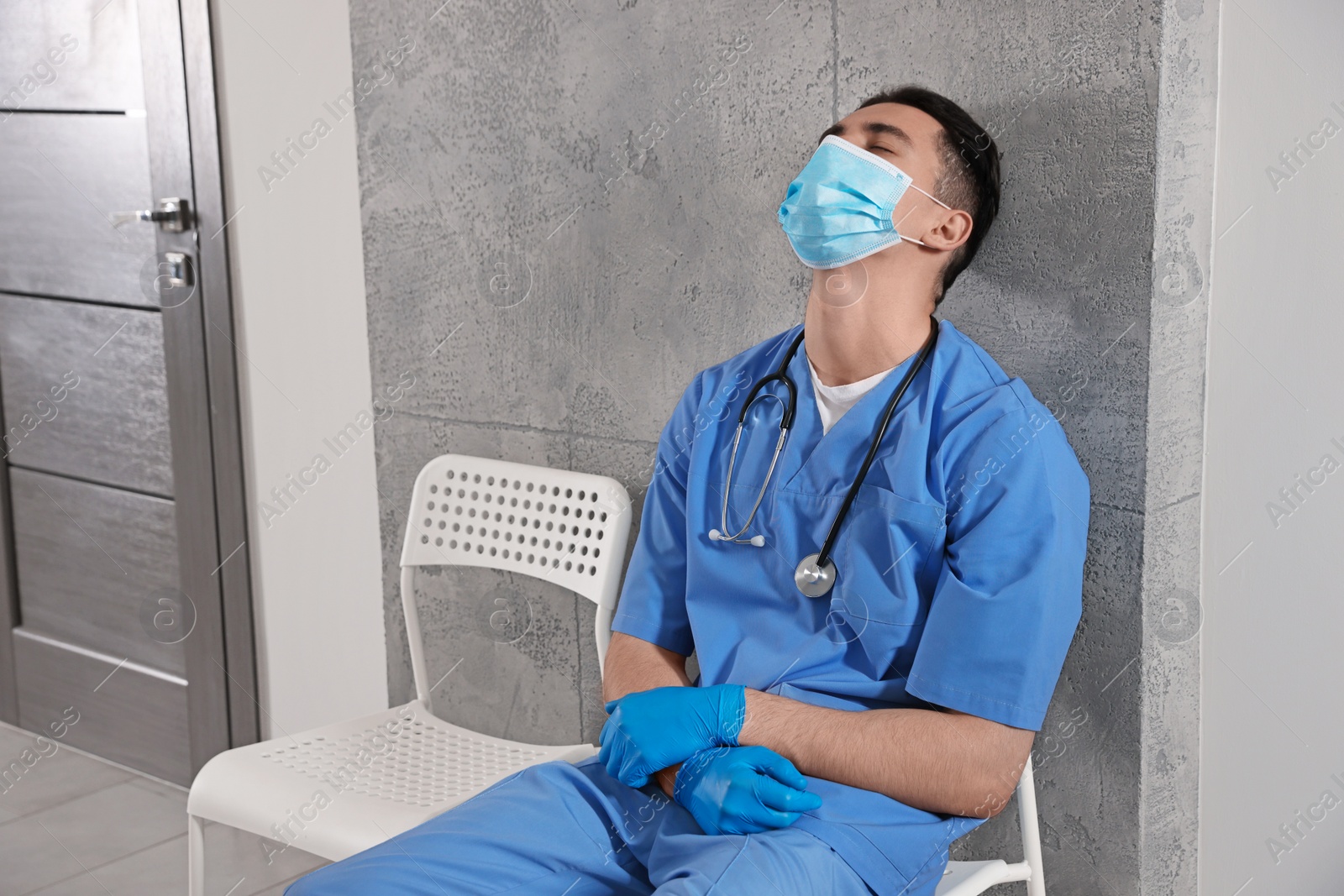 Photo of Exhausted doctor sleeping on chair in hospital hallway