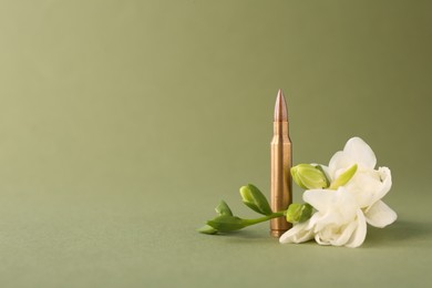 Bullet and beautiful freesia flowers on olive background, space for text