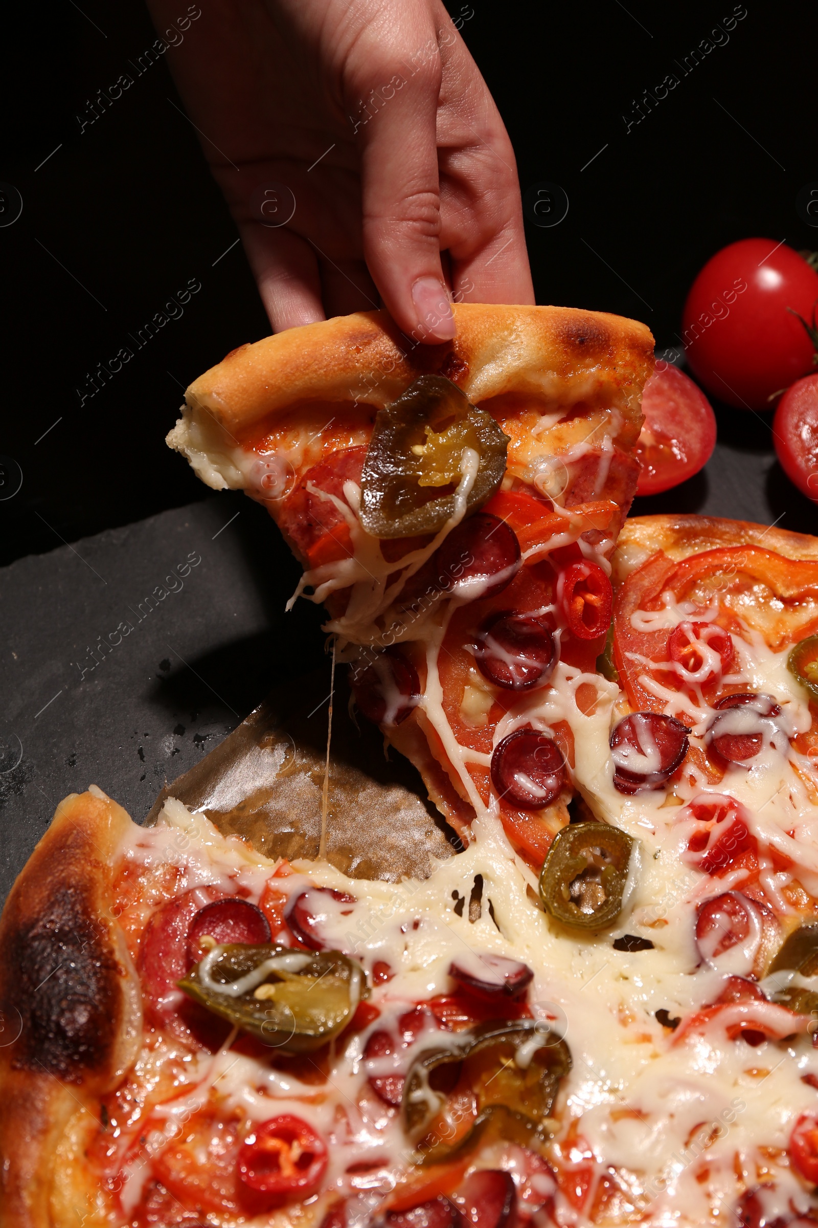 Photo of Woman taking piece of delicious pizza Diablo on black background, closeup