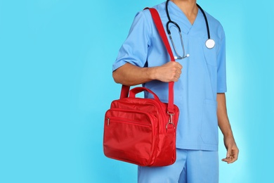 Photo of Male doctor with first aid kit and space for text on color background, closeup. Medical object