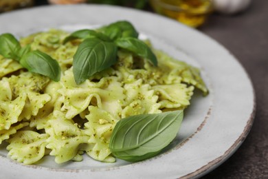 Delicious pasta with pesto sauce and basil on table, closeup