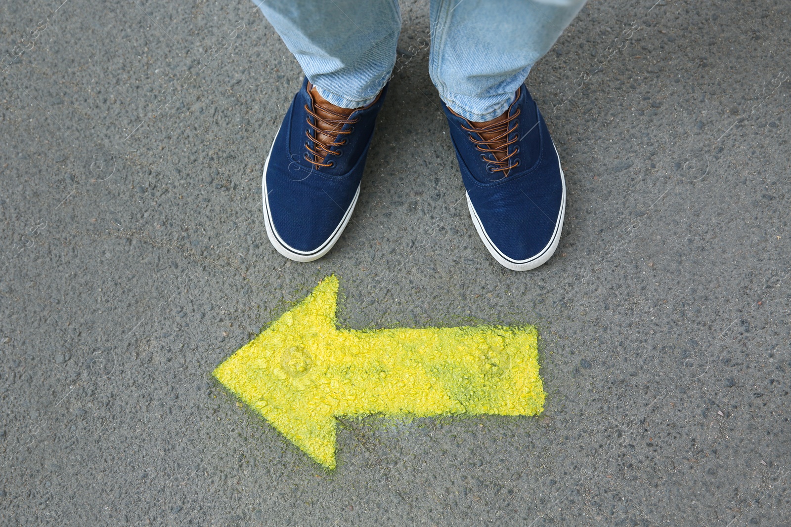 Photo of Man standing near arrow on asphalt, top view