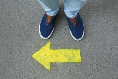 Photo of Man standing near arrow on asphalt, top view