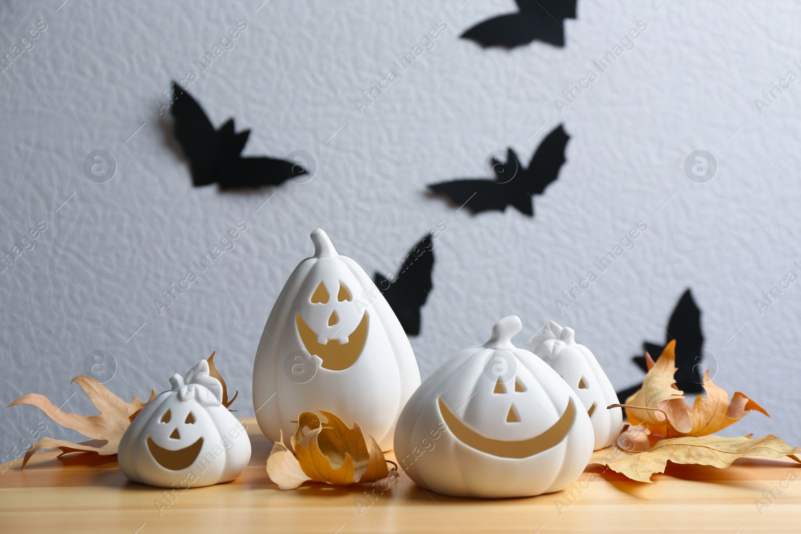 Photo of Composition with pumpkin shaped candle holders on wooden table. Halloween decoration