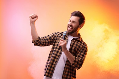 Photo of Handsome man with microphone singing in color lights