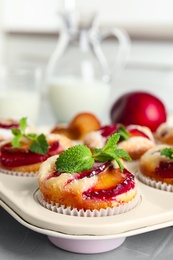 Delicious cupcakes with plums in baking pan, closeup