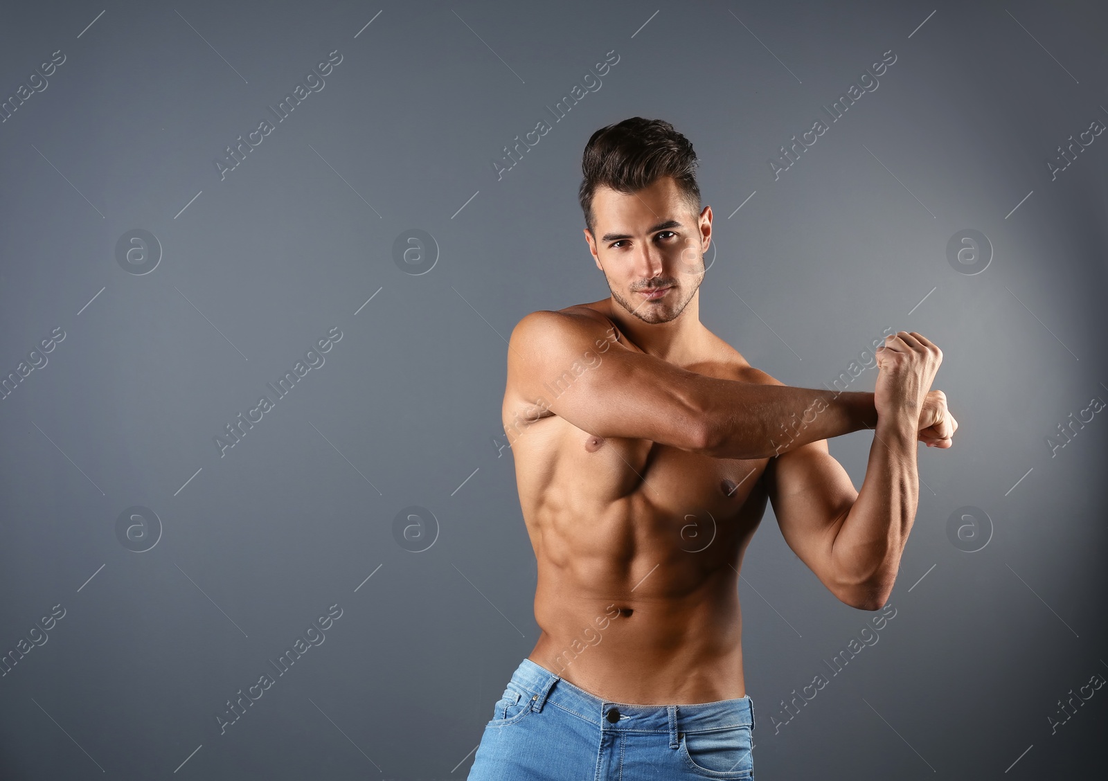 Photo of Shirtless young man in stylish jeans on grey background