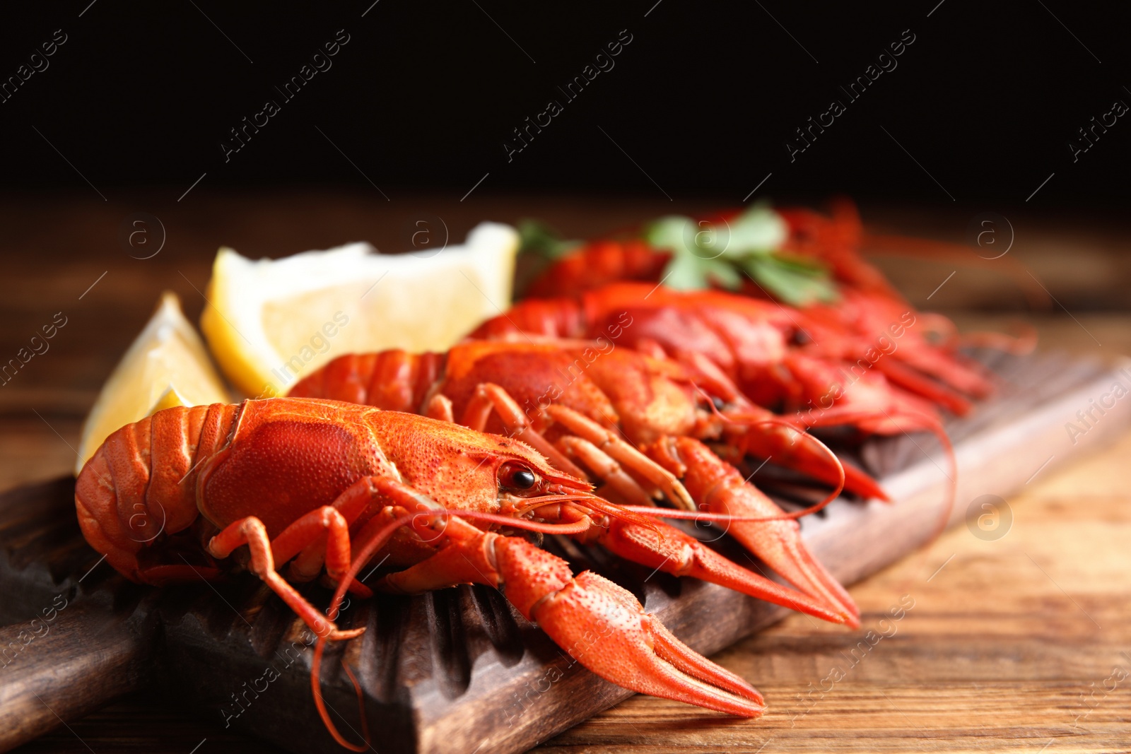 Photo of Delicious boiled crayfishes on wooden table, closeup