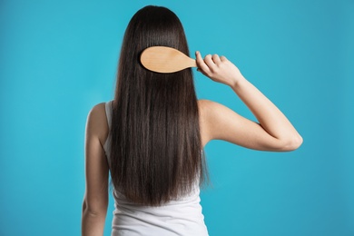 Photo of Back view of young woman with hair brush on color background