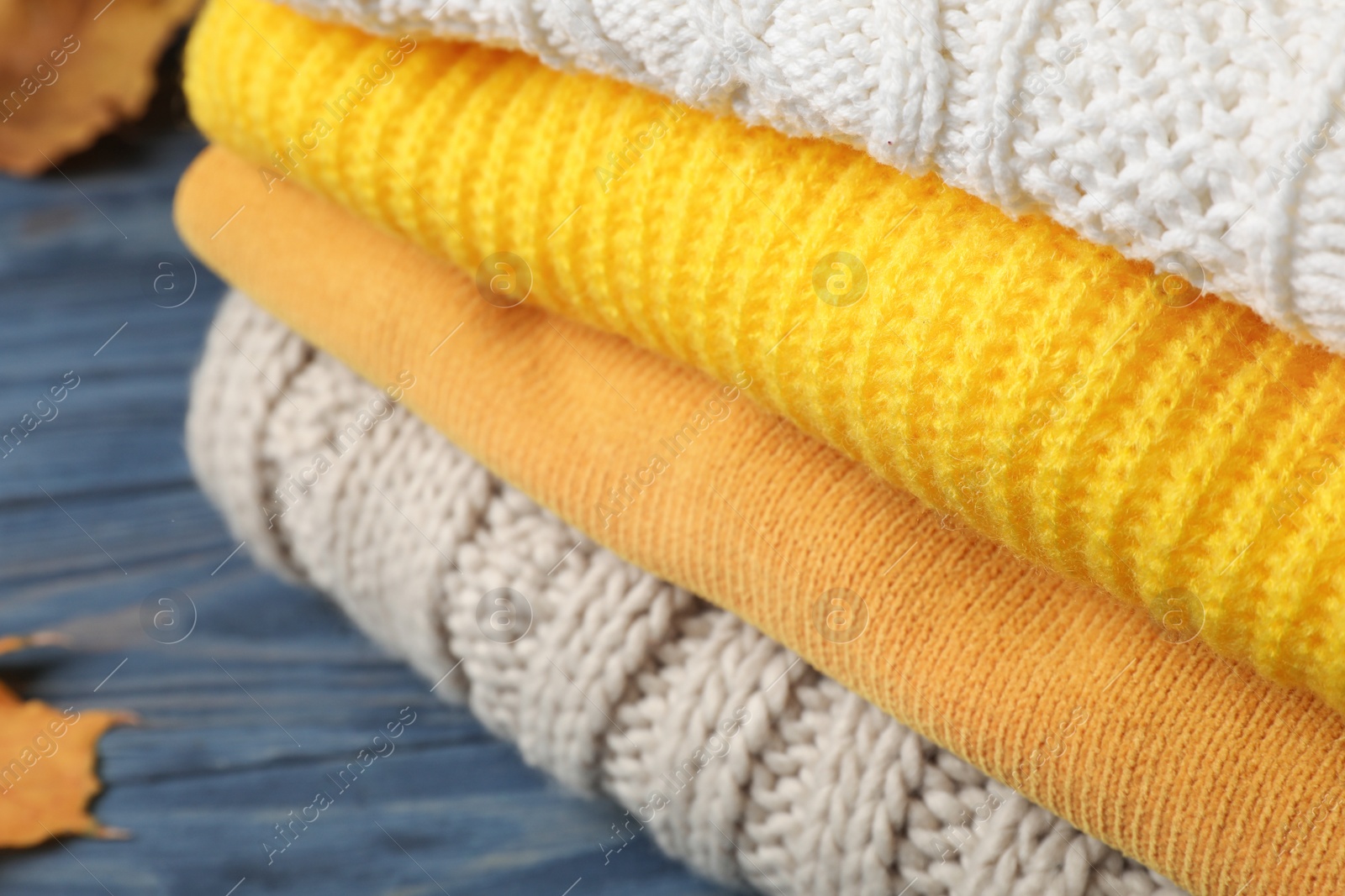 Photo of Stack of folded knitted sweaters on table, closeup