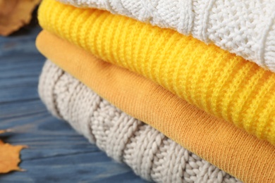 Photo of Stack of folded knitted sweaters on table, closeup