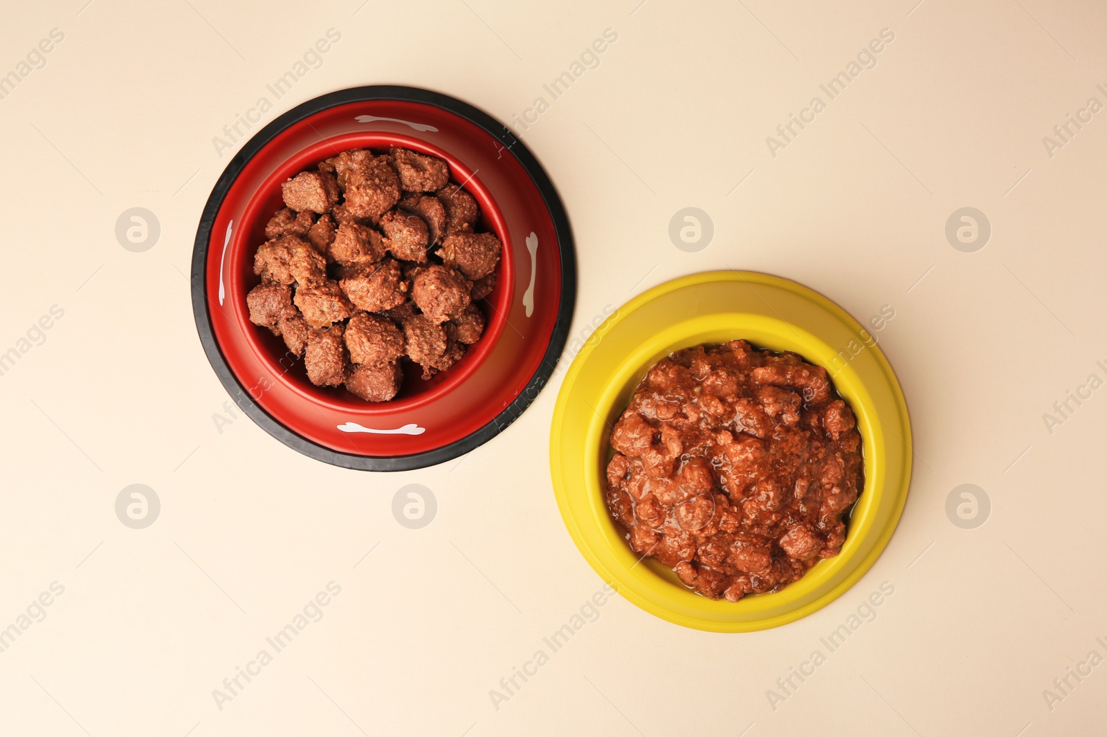 Photo of Wet pet food in feeding bowls on beige background, flat lay