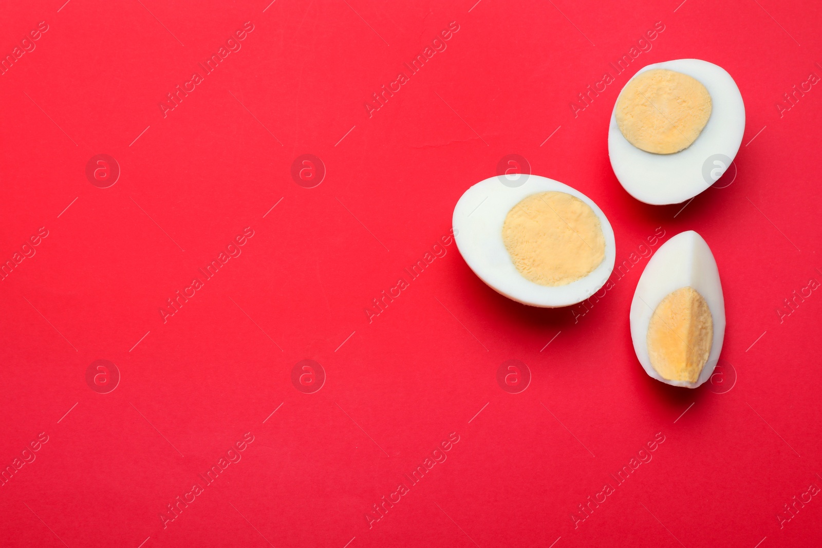 Photo of Cut fresh hard boiled eggs on red background, flat lay. Space for text