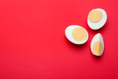 Photo of Cut fresh hard boiled eggs on red background, flat lay. Space for text