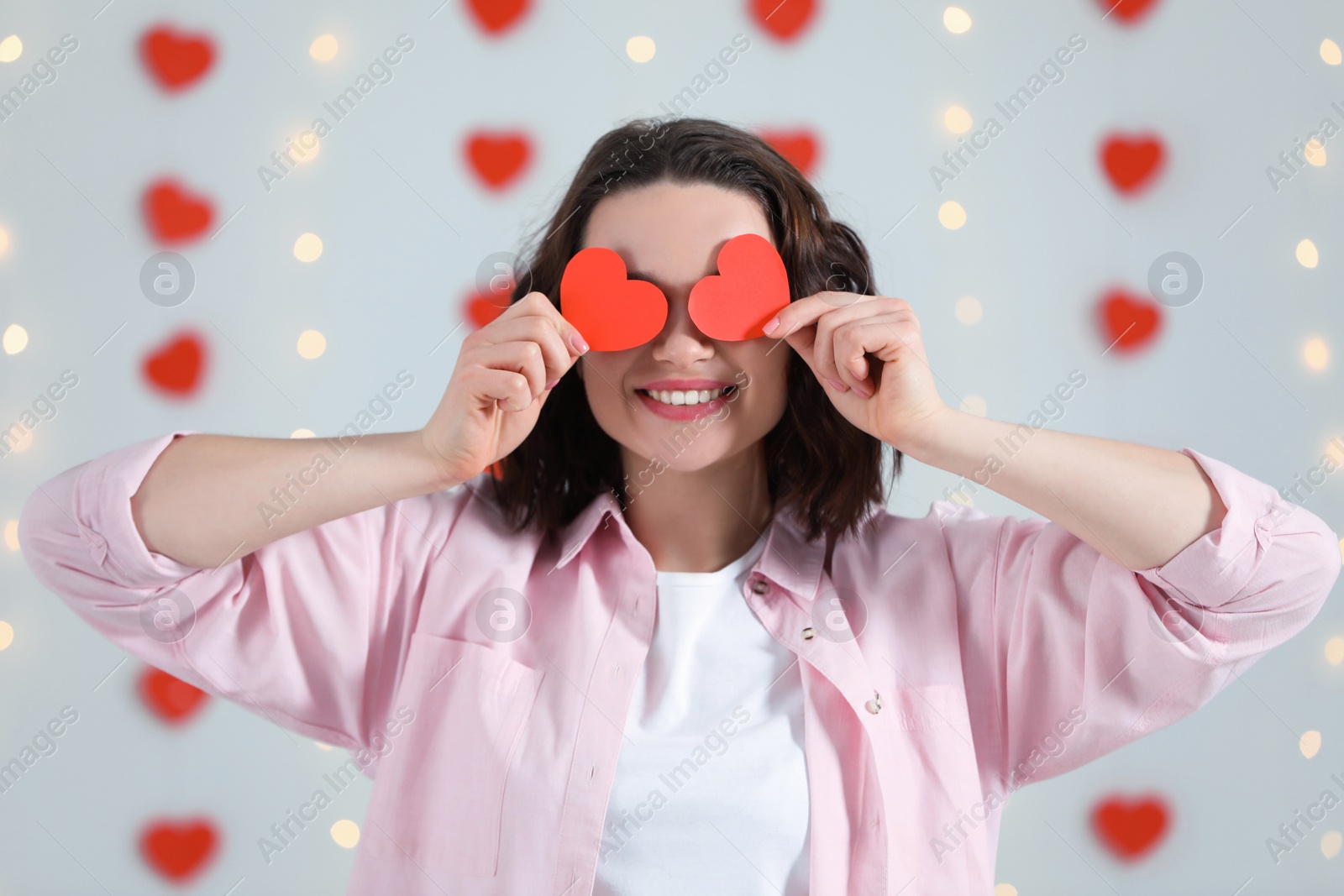 Photo of Beautiful young woman with red paper hearts indoors, view from camera. Valentine's day celebration in long distance relationship