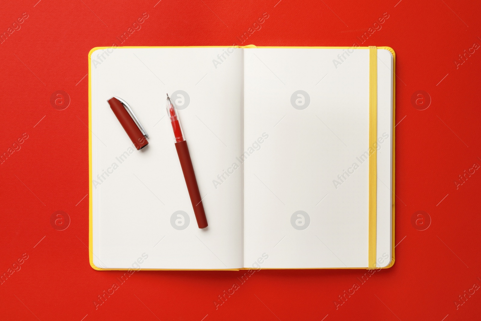 Photo of Notebook and pen on red background, top view