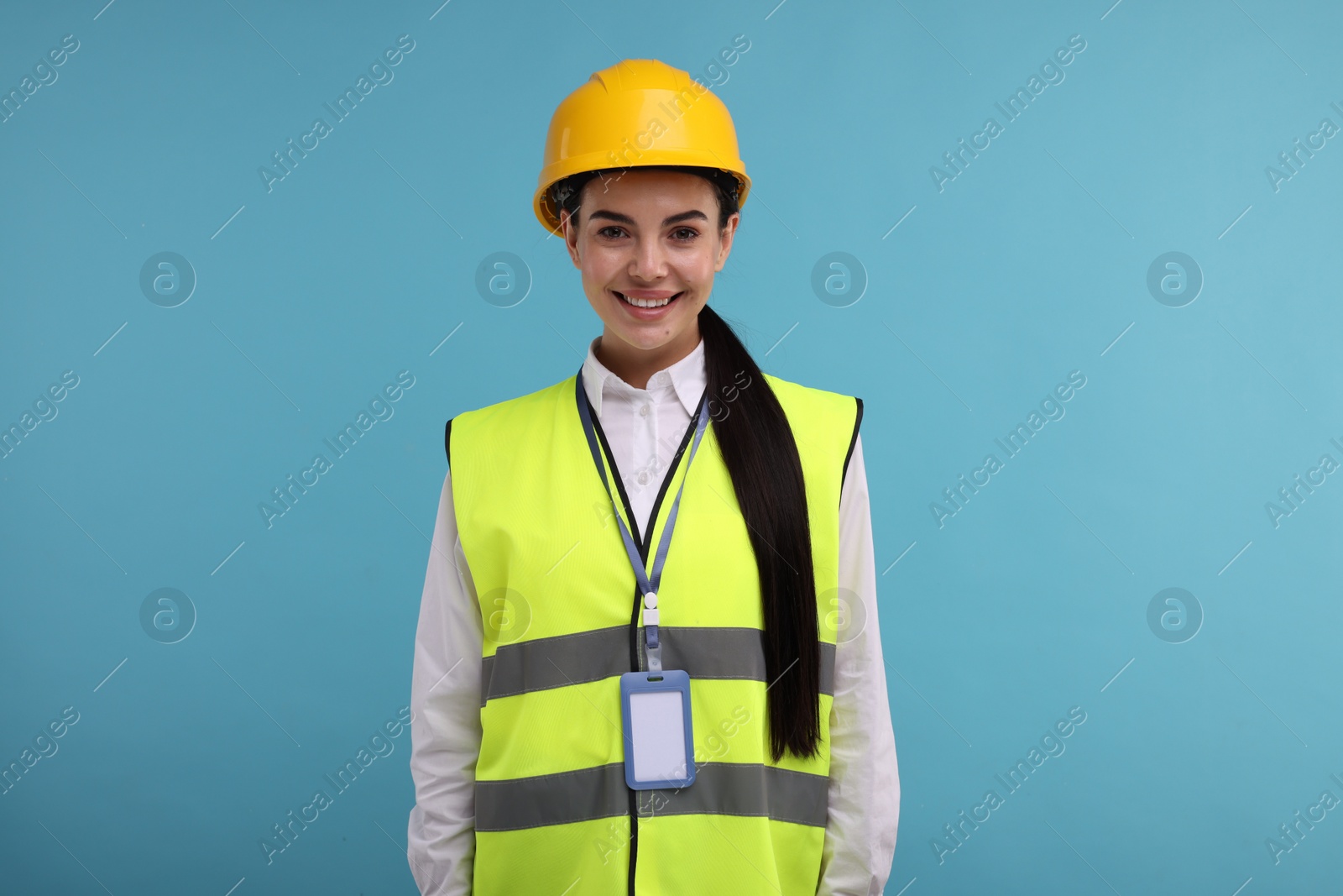 Photo of Engineer with hard hat and badge on light blue background