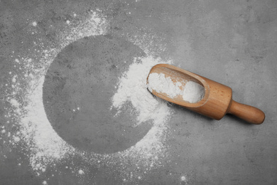 Flour and wooden scoop on light grey table, top view. Space for text