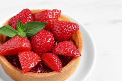 Photo of Tartlet with fresh strawberries on white marble table, closeup. Delicious dessert