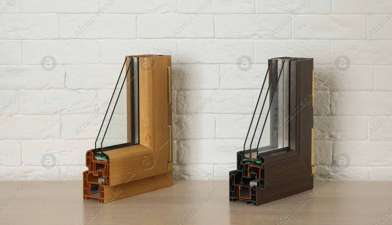 Photo of Samples of modern window profiles on table against brick wall. Installation service