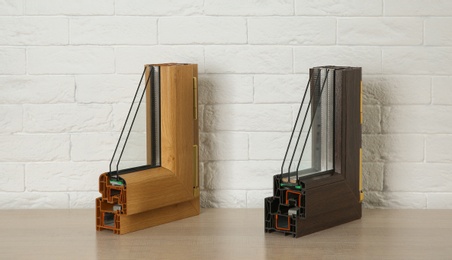 Samples of modern window profiles on table against brick wall. Installation service