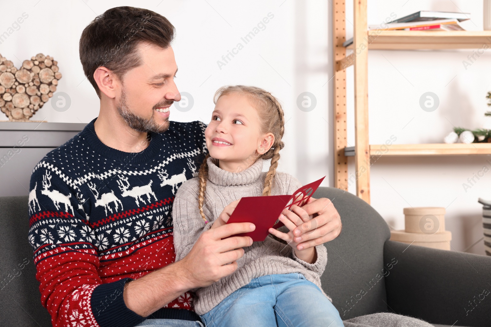 Photo of Happy man receiving greeting card from his daughter at home