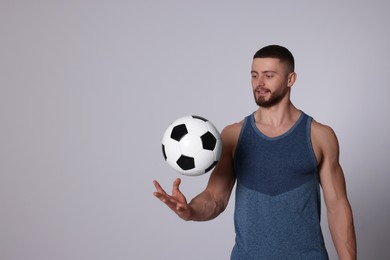 Photo of Athletic young man with soccer ball on light grey background. Space for text