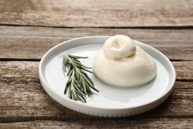 Photo of Delicious burrata cheese with rosemary on wooden table