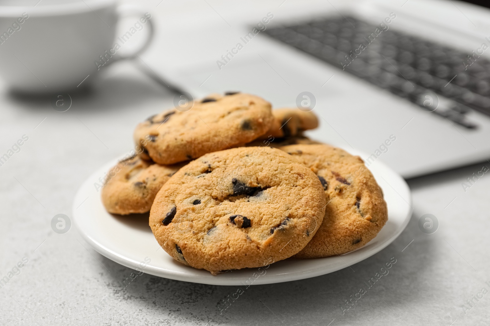 Photo of Chocolate chip cookies on light gray table in office, closeup