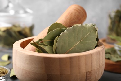 Photo of Bay leaves and pestle in wooden mortar, closeup