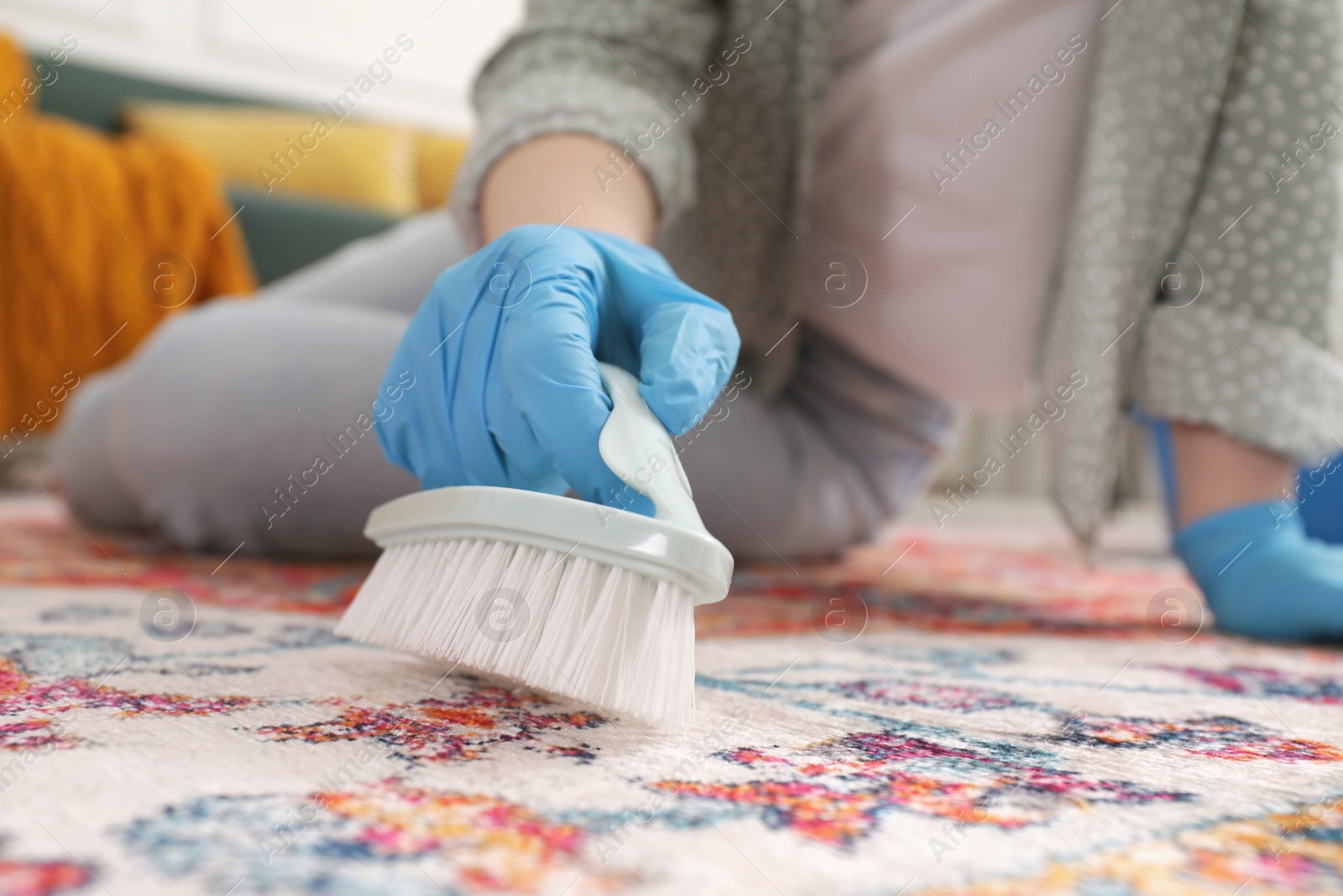 Photo of Woman cleaning carpet with brush indoors, closeup. Space for text