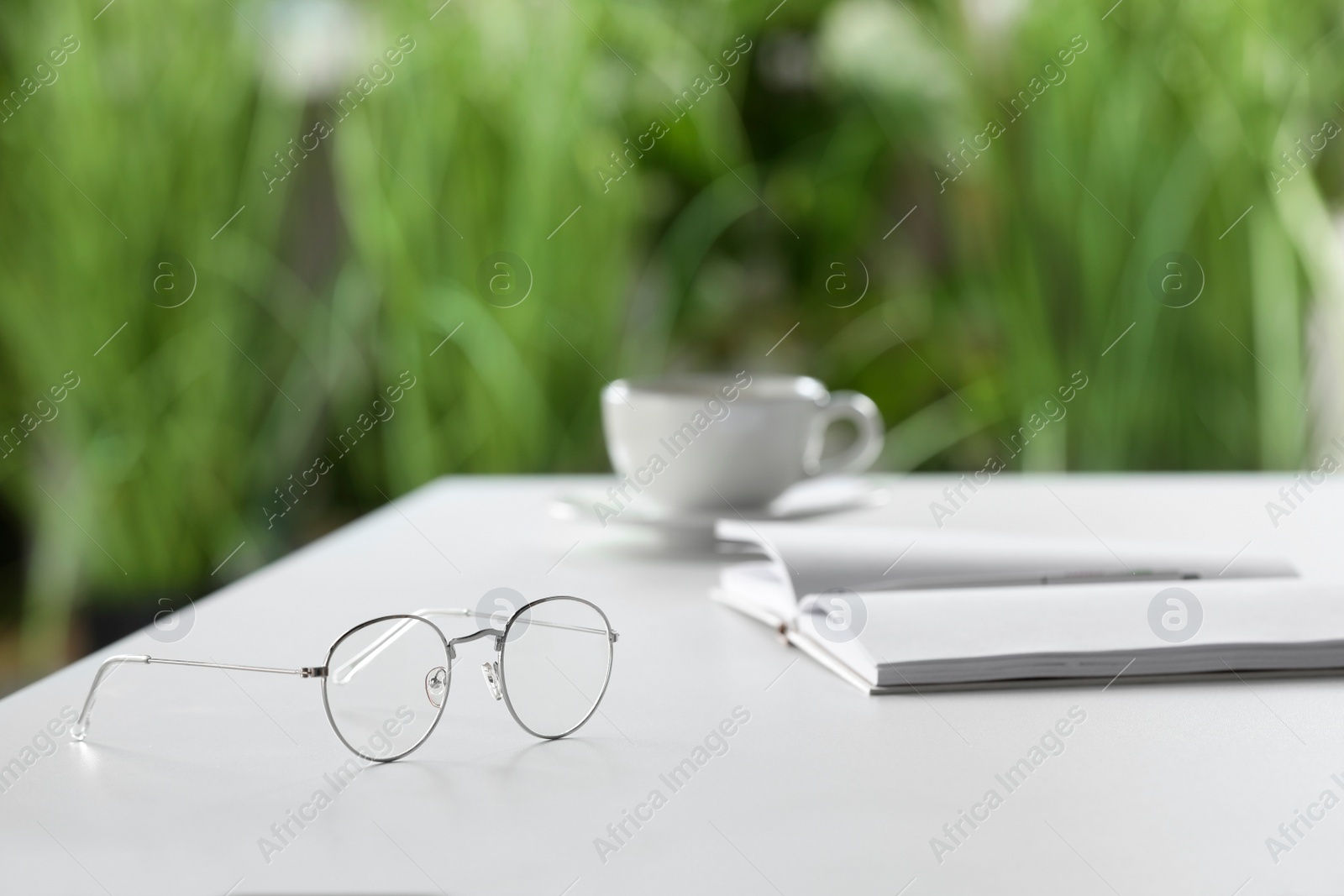 Photo of Stylish glasses and notebook on white table indoors