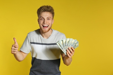 Photo of Young man with money on color background. Space for text