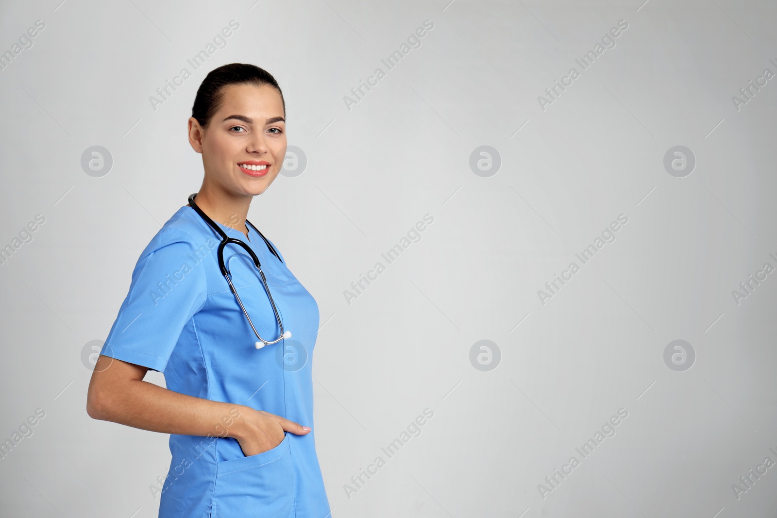 Photo of Portrait of young medical assistant with stethoscope on color background. Space for text