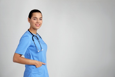 Portrait of young medical assistant with stethoscope on color background. Space for text