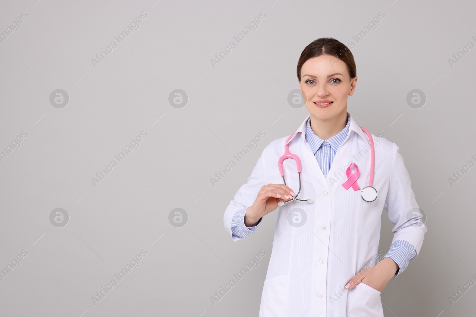 Photo of Mammologist with pink ribbon on grey background, space for text. Breast cancer awareness