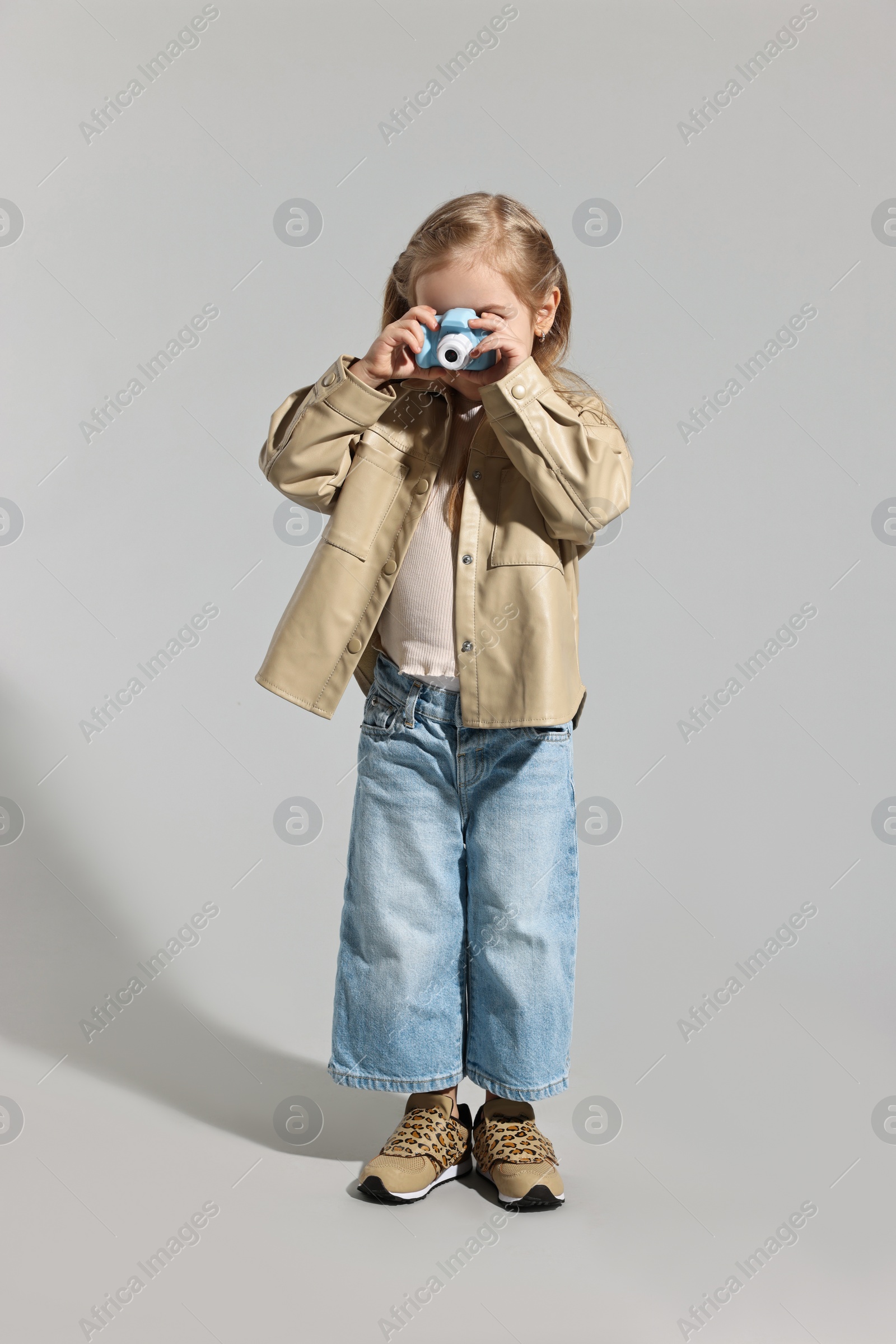 Photo of Fashion concept. Stylish girl with toy camera on light grey background