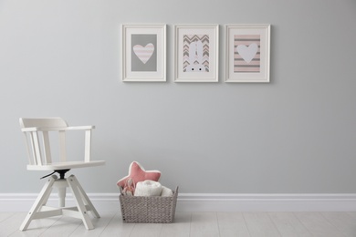 Photo of Stylish baby room interior with chair and cute pictures on wall
