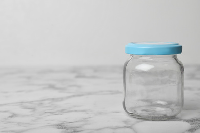 Empty glass jar on white marble table, space for text