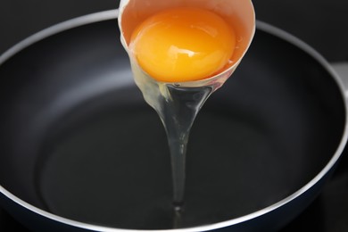 Adding raw egg into frying pan, closeup