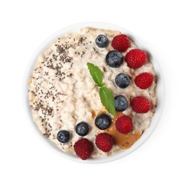 Photo of Tasty boiled oatmeal with berries, chia seeds and peanut butter in bowl isolated on white, top view