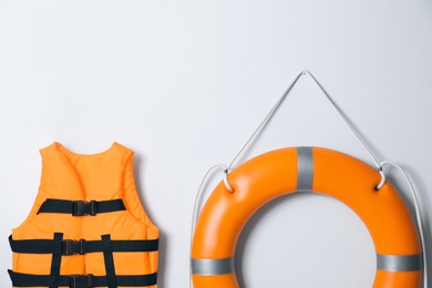 Orange life jacket and lifebuoy on light background. Rescue equipment