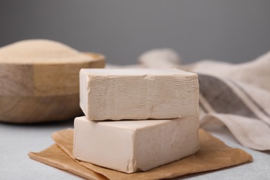 Photo of Blocks of compressed yeast on light gray table, closeup