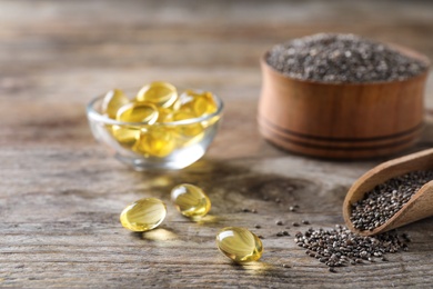 Chia oil capsules and scoop with seeds on table. Space for text