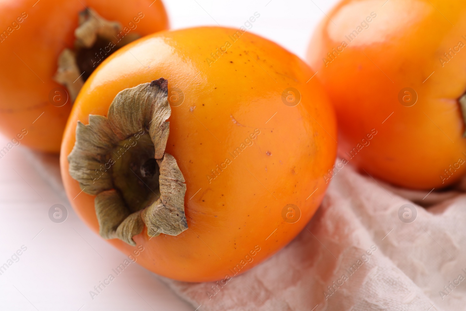 Photo of Delicious ripe persimmons on white table, closeup