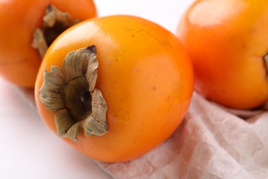 Photo of Delicious ripe persimmons on white table, closeup