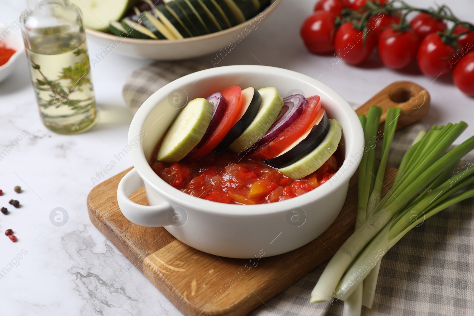 Photo of Dressing for ratatouille with different fresh vegetables on white marble table, closeup