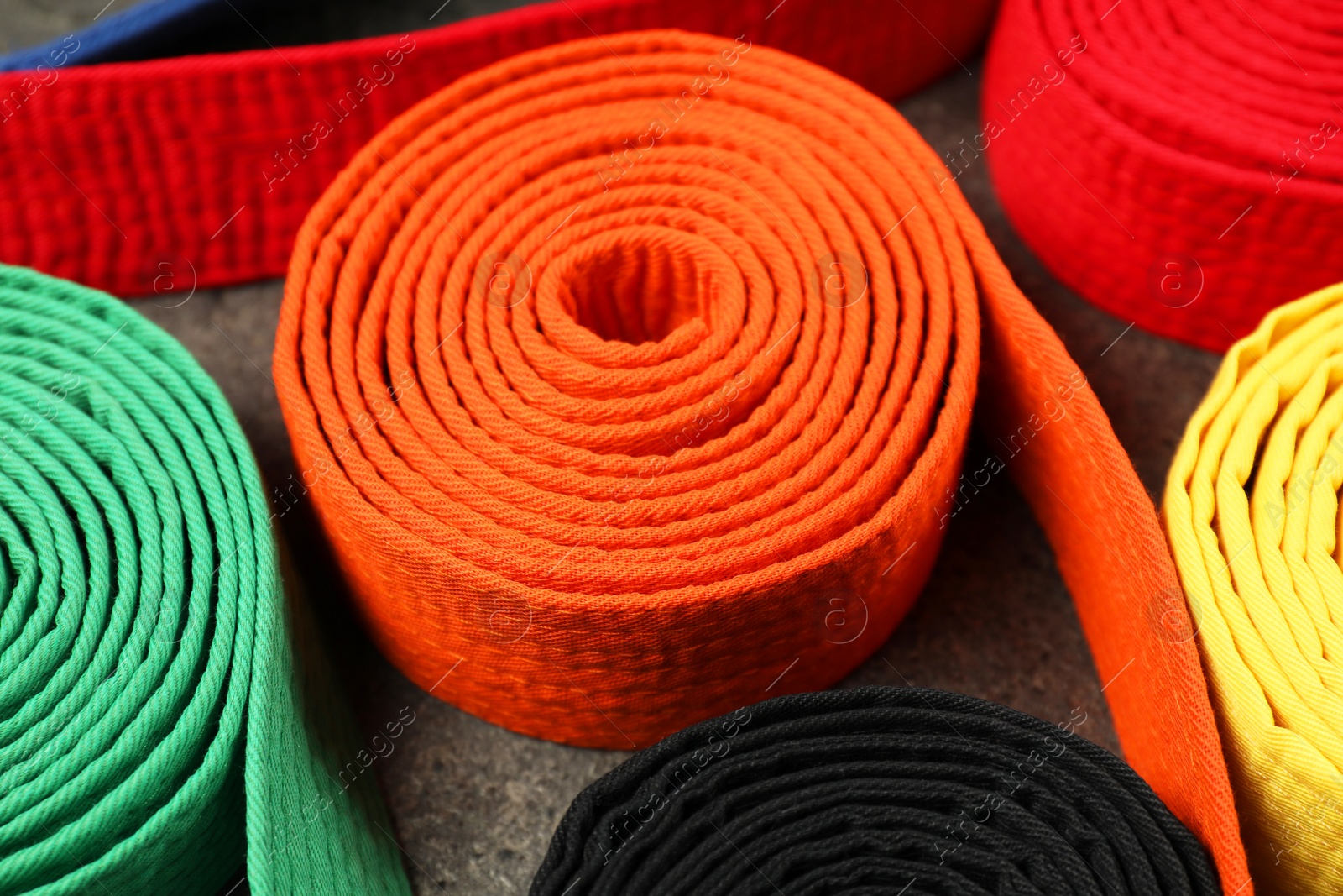 Photo of Colorful karate belts, closeup. Martial arts uniform