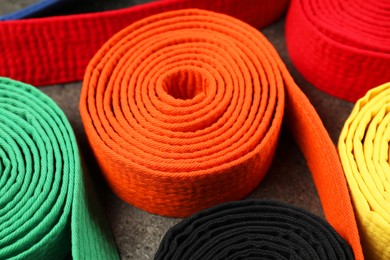 Photo of Colorful karate belts, closeup. Martial arts uniform