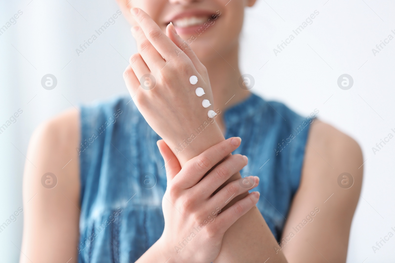 Photo of Young woman applying hand cream at home, closeup